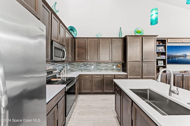 kitchen with backsplash, sink, decorative light fixtures, dark brown cabinetry, and stainless steel appliances