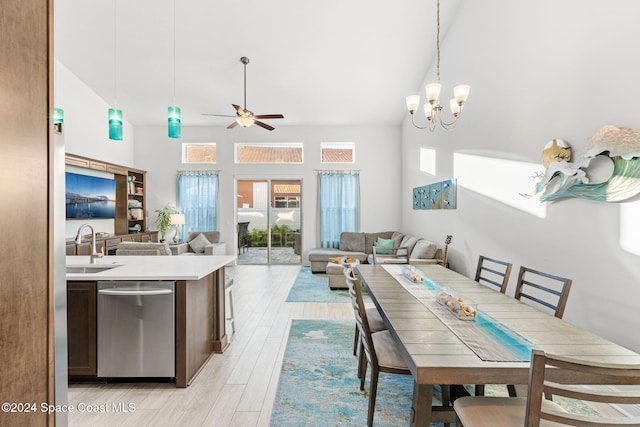 dining space featuring ceiling fan with notable chandelier, light hardwood / wood-style floors, sink, and a high ceiling