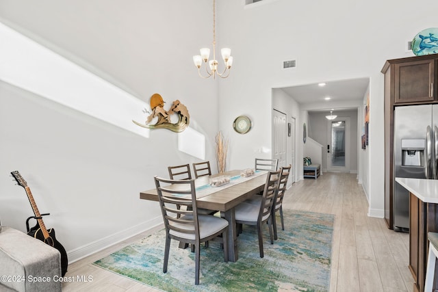 dining room featuring a notable chandelier, a high ceiling, and light hardwood / wood-style flooring