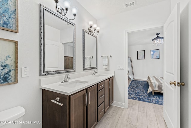 bathroom featuring vanity, a textured ceiling, an inviting chandelier, hardwood / wood-style floors, and toilet