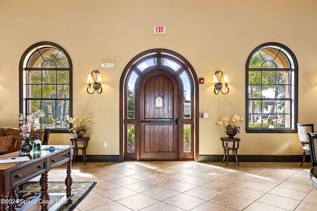 tiled entrance foyer featuring a high ceiling and a healthy amount of sunlight