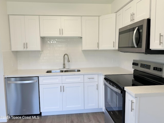 kitchen with decorative backsplash, stainless steel appliances, sink, white cabinets, and light hardwood / wood-style floors