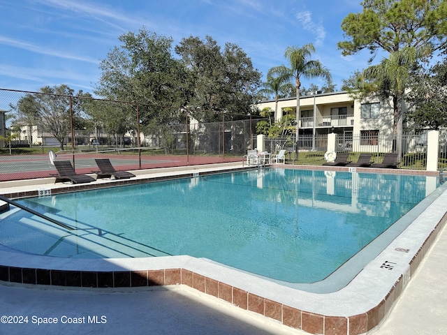 view of swimming pool featuring tennis court