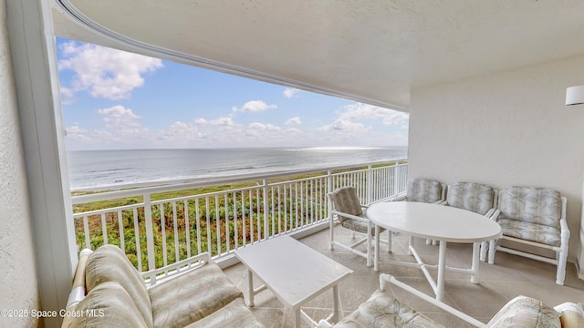 balcony featuring a view of the beach and a water view