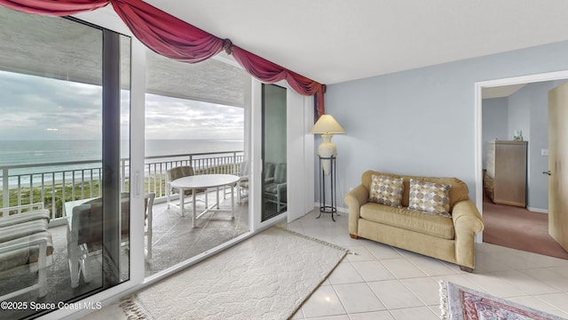 tiled living room featuring a wall of windows and a water view