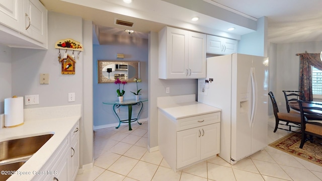 kitchen featuring sink, white cabinets, light tile patterned floors, and white refrigerator with ice dispenser