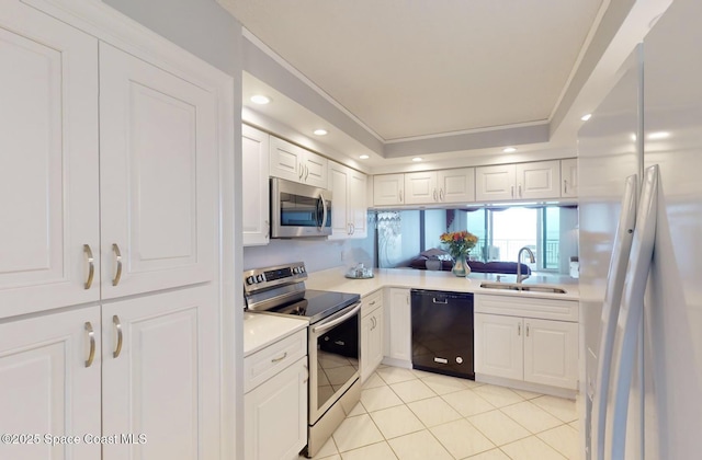 kitchen with stainless steel appliances, sink, white cabinetry, light tile patterned floors, and a tray ceiling