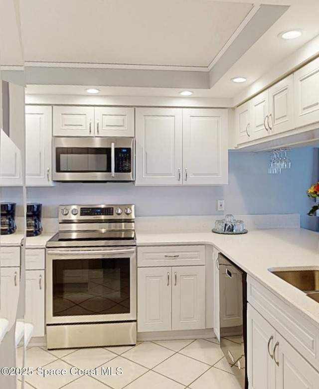 kitchen with stainless steel appliances, white cabinetry, a raised ceiling, and light tile patterned floors