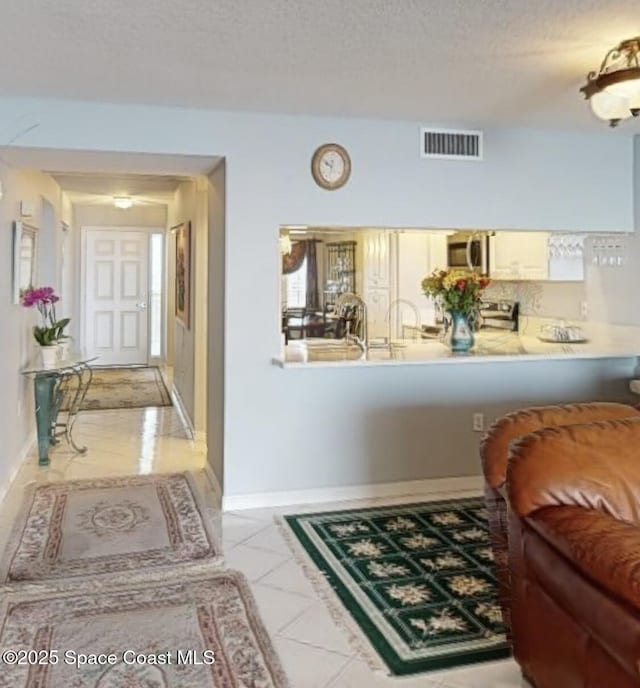 hallway featuring a textured ceiling and light tile patterned floors