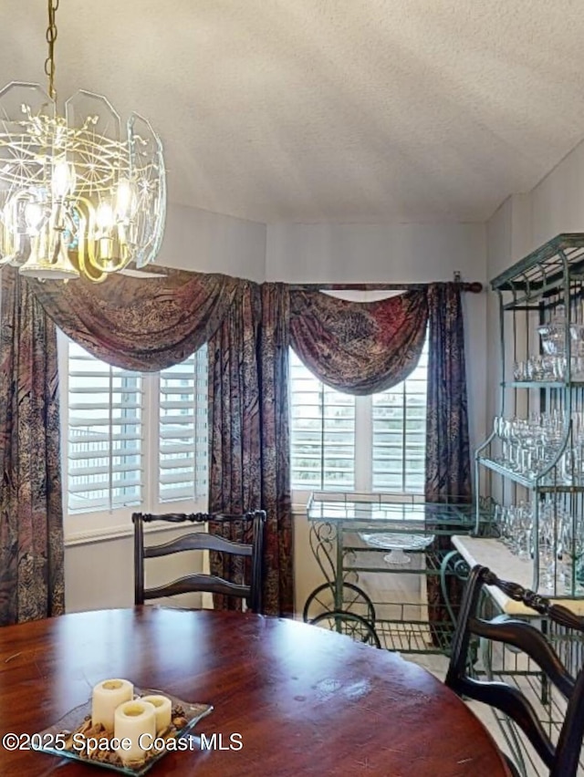 dining area with a textured ceiling, a healthy amount of sunlight, and a notable chandelier