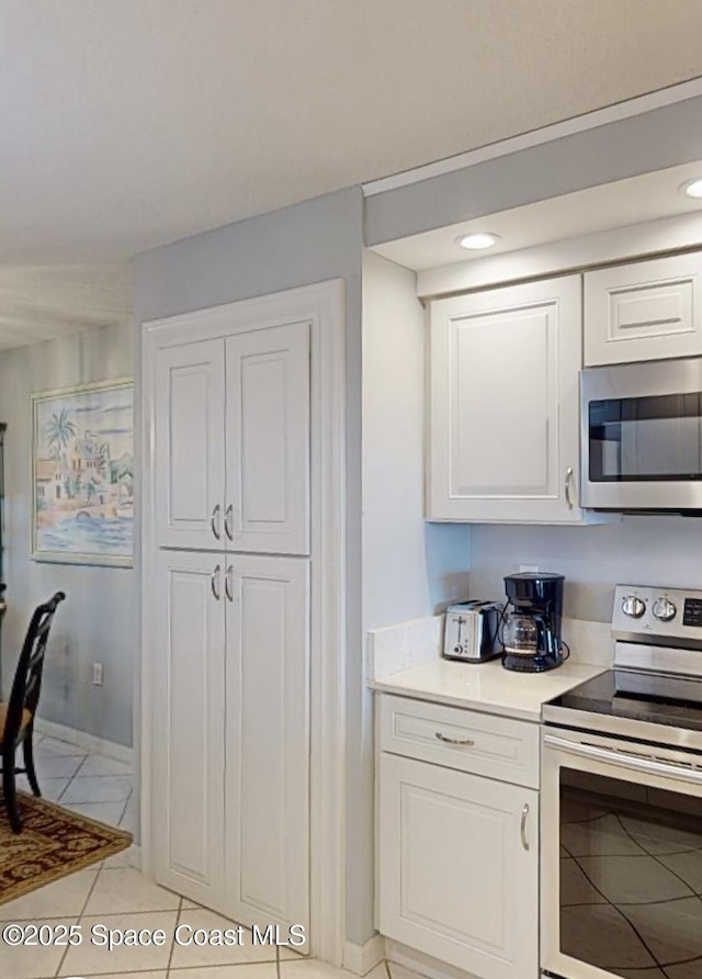 kitchen featuring white cabinets, appliances with stainless steel finishes, and light tile patterned floors