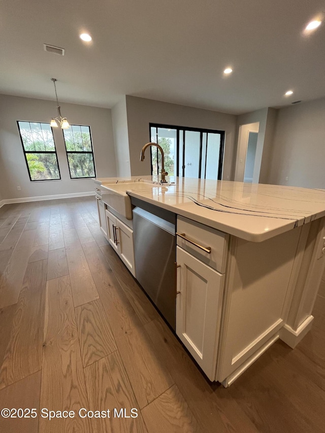 kitchen featuring stainless steel dishwasher, an island with sink, and white cabinetry