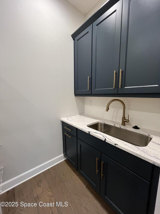 kitchen with light stone counters, sink, decorative backsplash, and dark hardwood / wood-style flooring