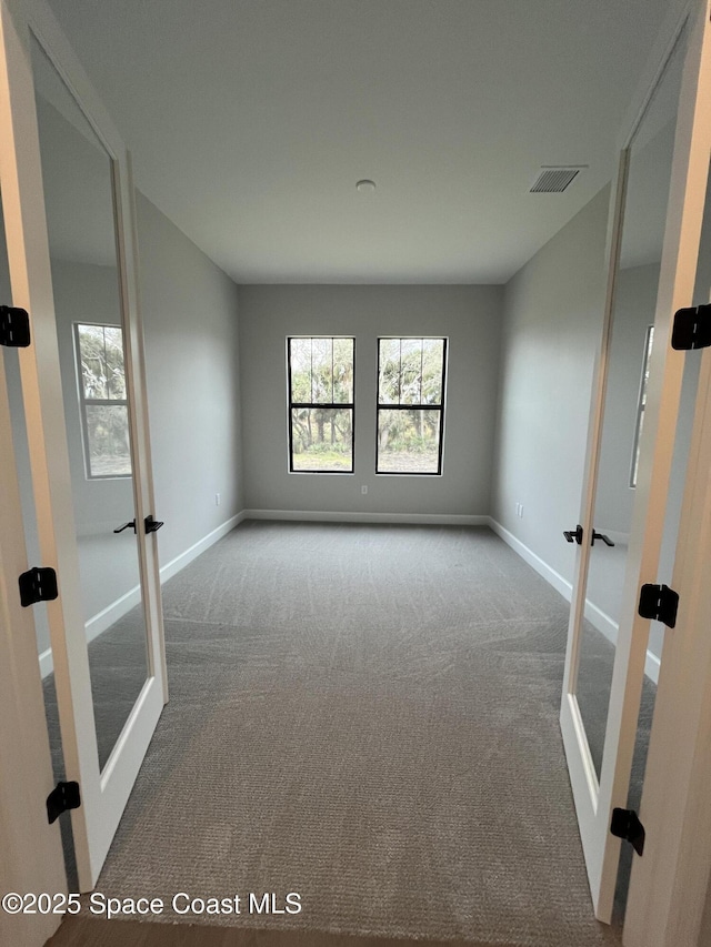 carpeted spare room featuring french doors