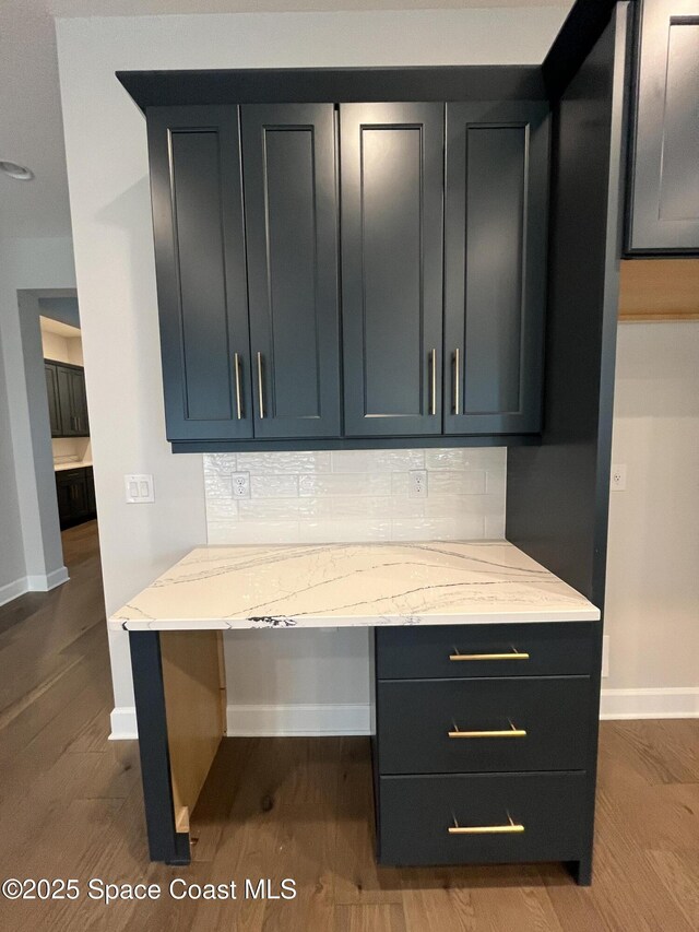 interior space featuring hardwood / wood-style floors, backsplash, and light stone counters