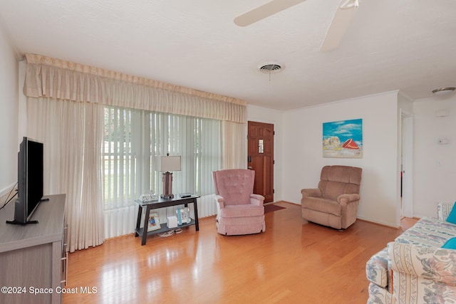 living room featuring light wood-type flooring, ceiling fan, and ornamental molding