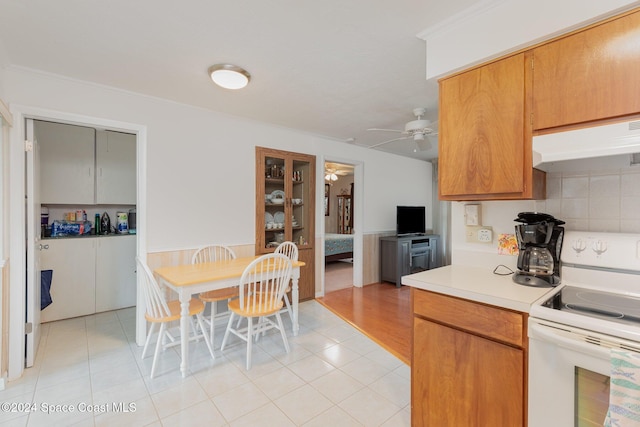 kitchen featuring crown molding, light tile patterned flooring, white electric range oven, and ceiling fan