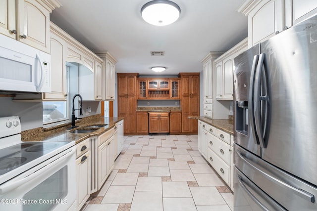 kitchen with sink, white appliances, and dark stone counters