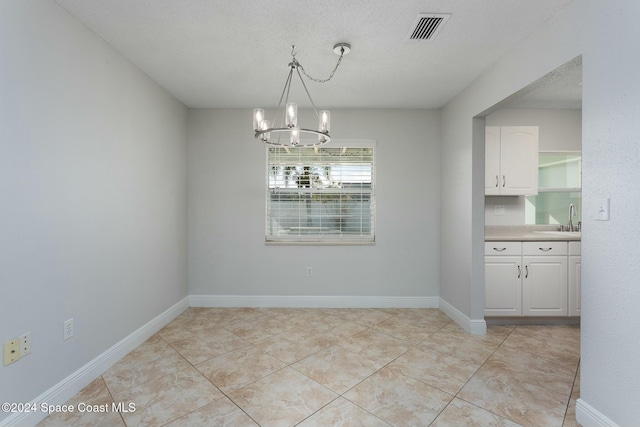 unfurnished dining area with a textured ceiling, a notable chandelier, light tile patterned flooring, and sink