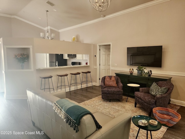 living room featuring lofted ceiling, dark wood-type flooring, crown molding, and a notable chandelier