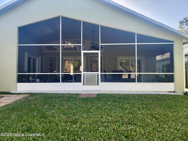 rear view of house featuring a sunroom and a yard