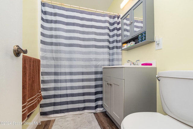 bathroom with wood-type flooring, vanity, toilet, and walk in shower