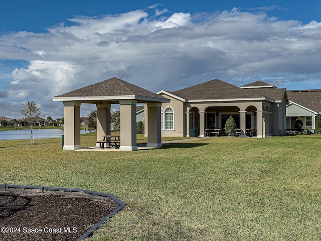 back of property featuring a water view and a lawn