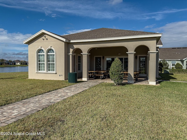 rear view of house with a lawn and a water view