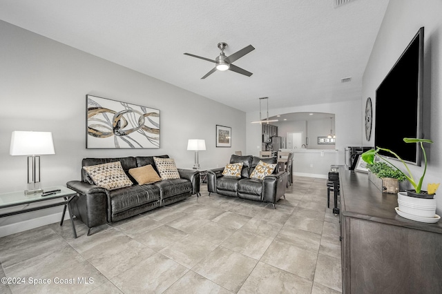 living room featuring ceiling fan and a textured ceiling