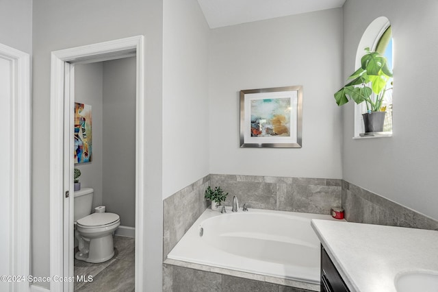 bathroom featuring vanity, toilet, and tiled tub