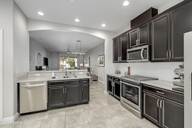 kitchen featuring appliances with stainless steel finishes, tasteful backsplash, sink, light tile patterned floors, and decorative light fixtures