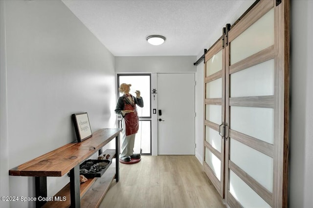 interior space with light hardwood / wood-style floors, a barn door, and a textured ceiling