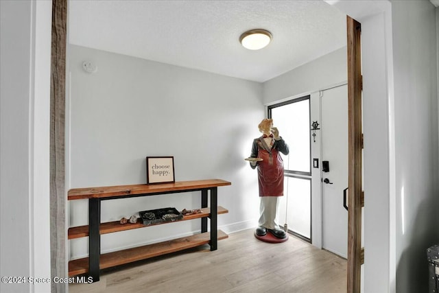 foyer entrance with light wood-type flooring and a textured ceiling