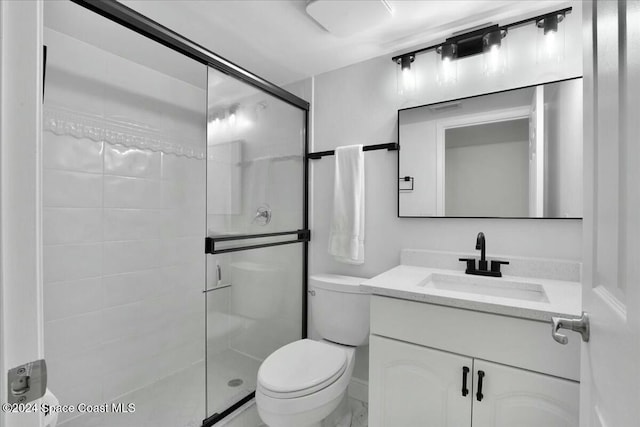 bathroom featuring vanity, toilet, and a shower with shower door