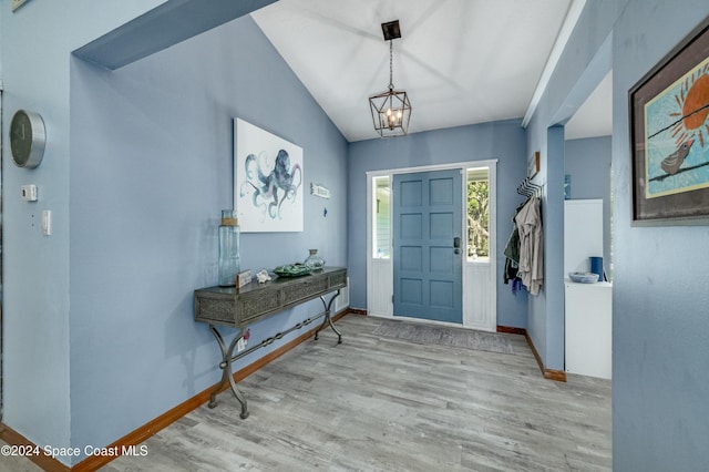 entrance foyer with light wood-type flooring, vaulted ceiling, and a notable chandelier