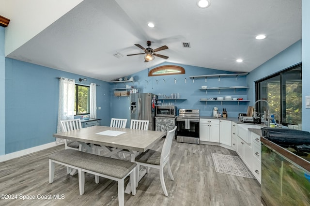 kitchen featuring appliances with stainless steel finishes, vaulted ceiling, sink, white cabinets, and light hardwood / wood-style floors