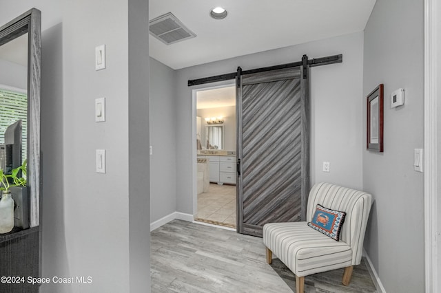 hall featuring light wood-type flooring and a barn door