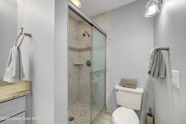 bathroom featuring tile patterned floors, vanity, a shower with shower door, and toilet