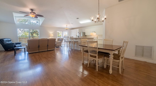 dining area with ceiling fan with notable chandelier, wood-type flooring, and vaulted ceiling