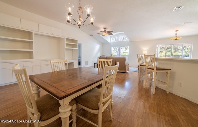 dining area featuring built in shelves, light hardwood / wood-style flooring, a textured ceiling, lofted ceiling, and ceiling fan with notable chandelier