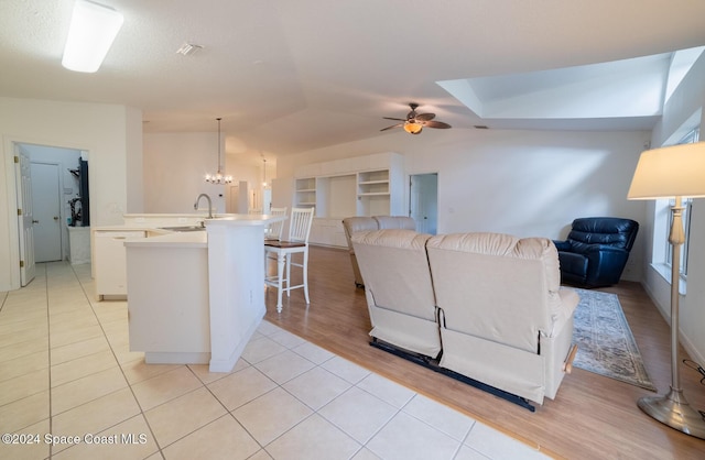 living room featuring light tile patterned floors, ceiling fan with notable chandelier, built in features, and sink