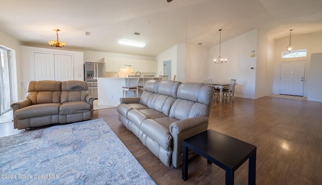 living room featuring dark hardwood / wood-style floors, an inviting chandelier, and lofted ceiling