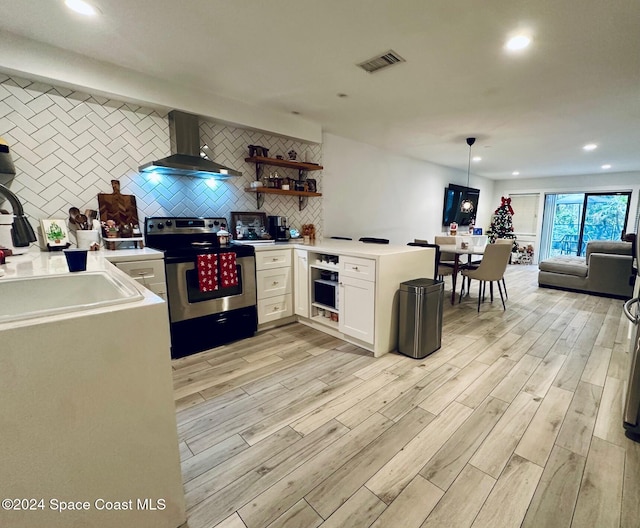 kitchen featuring wall chimney exhaust hood, pendant lighting, light hardwood / wood-style floors, electric stove, and white cabinets