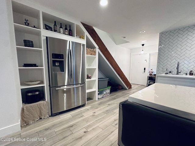 kitchen featuring stainless steel fridge, backsplash, and light hardwood / wood-style flooring