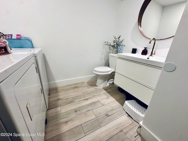 bathroom featuring independent washer and dryer, vanity, toilet, and hardwood / wood-style floors