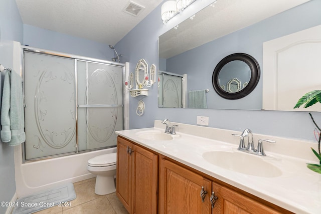 full bathroom with vanity, shower / bath combination with glass door, tile patterned flooring, toilet, and a textured ceiling