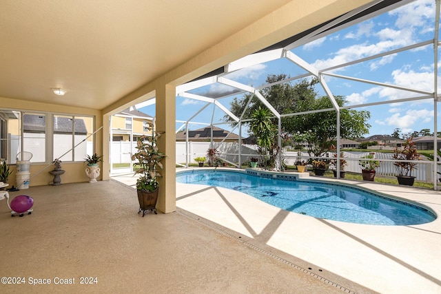 view of swimming pool featuring glass enclosure and a patio area