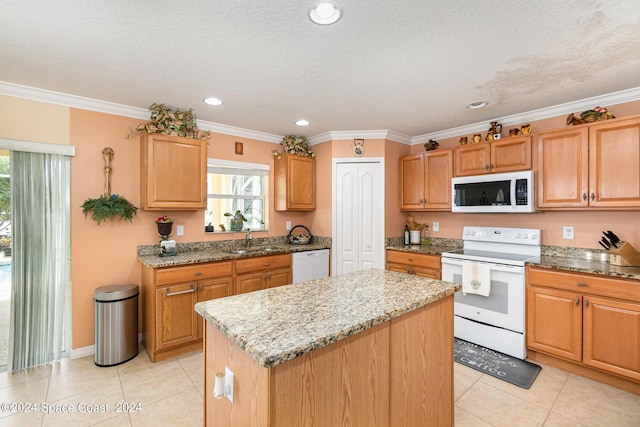 kitchen featuring light stone counters, a textured ceiling, white appliances, crown molding, and a center island