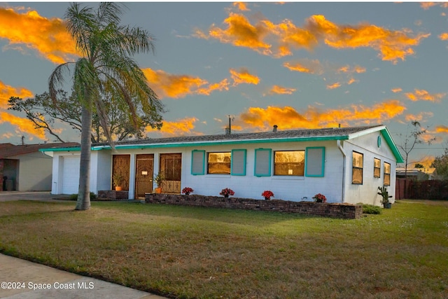 single story home featuring a lawn and a garage