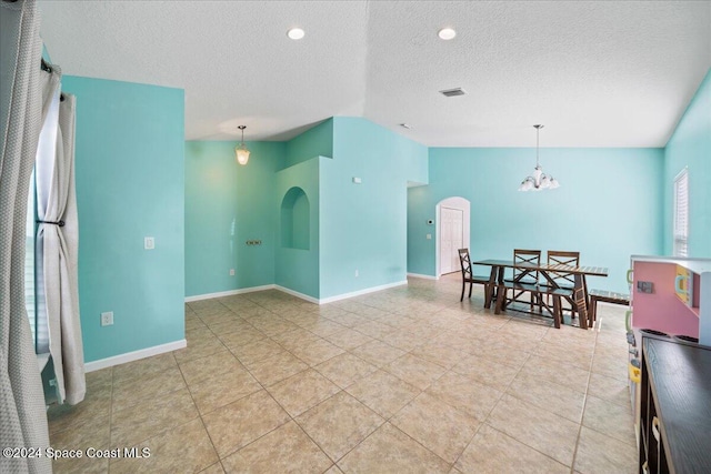 interior space with a chandelier, a textured ceiling, and vaulted ceiling